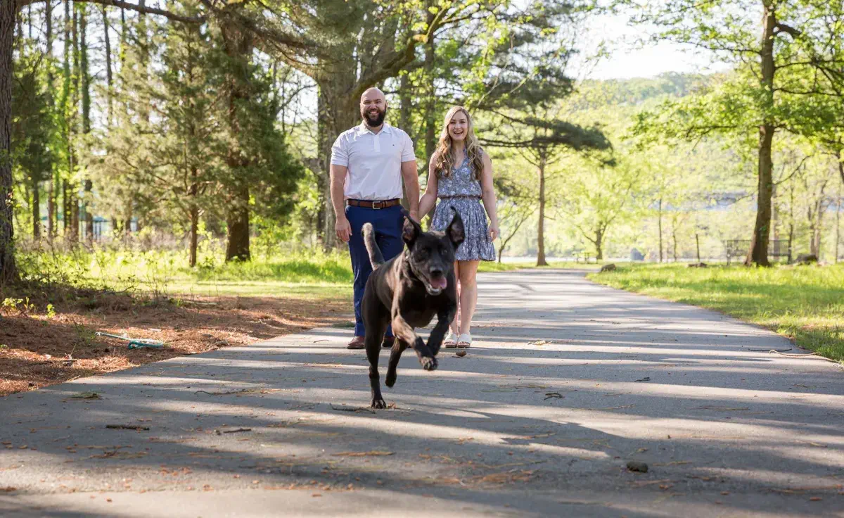 Engaged couple walking through open field during Two Rivers Park engagement session in Little Rock, Arkansas
